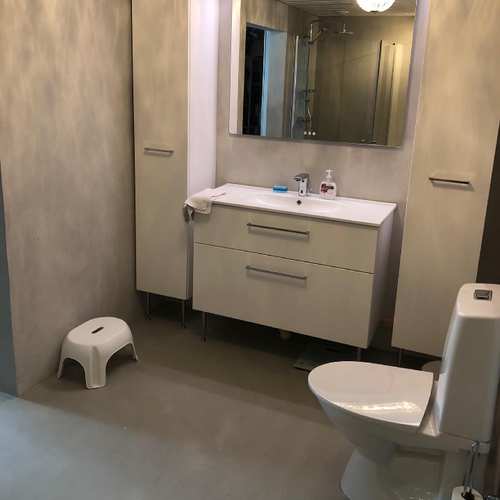 Grått badrum med vit toalett