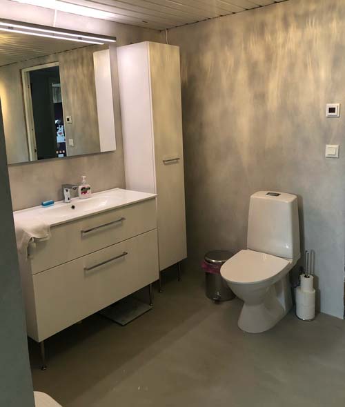Grått badrum med vit toalett